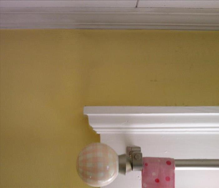 yellow wall with a curtain rod showing damage from soot